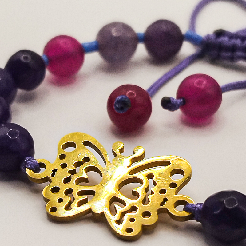 دستبند سنگ عقیق بنفش و سرخابی پلاک پروانه بلتا گالری مدل دایانا 9 تصویر کلوزآپ از پلاک پروانه طلایی در میان سنگهای عقیق