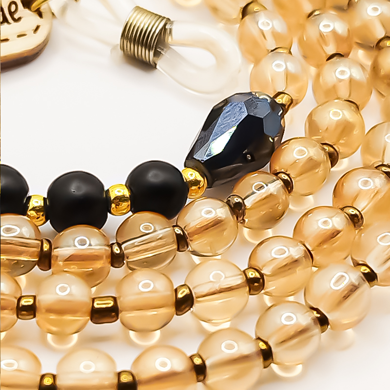 بندعینک زنانه بلتاگالری مدل گندمزار 2 از مهرههای سیلیس عسلی، کریستال شفاف و انیکس مات ساخته شده است. رنگها نه فریاد میزنند، نه خاموشاند — متعادل و باشکوهاند. پلاکهای چوبی دستساز در دو سر بند، امضای اصالتاند. بندعینک زنانه بلتاگالری مدل گندمزار